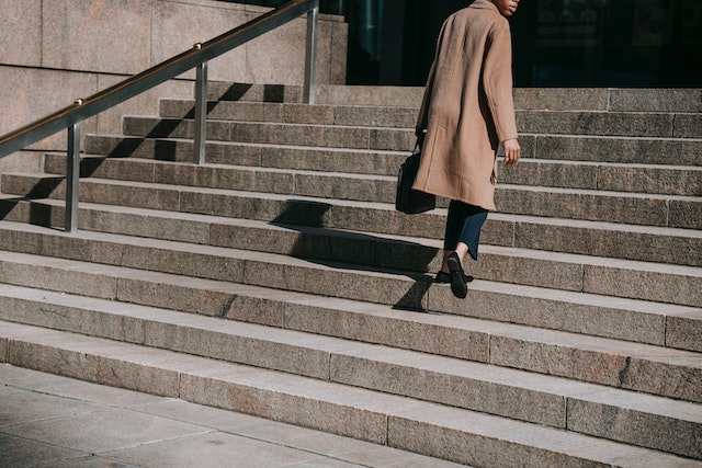 photo of a woman walking up concrete steps outside a building