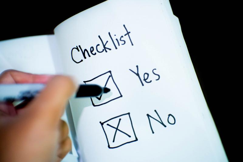 person ticking the box for yes on a piece of paper with checklist at the top and yes or no checkboxes