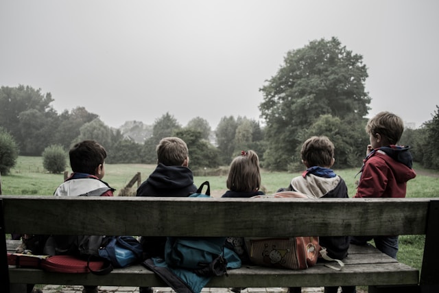 photo of 5 children sitting on a park bench