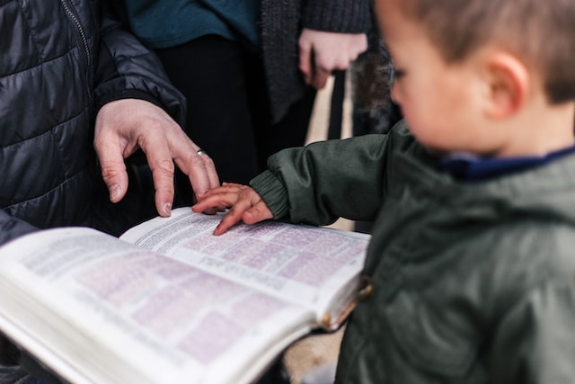 photo of a young child touching a book held in the hands of an older person
