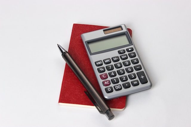 photo of a calculate and pen sitting on top of a notebook