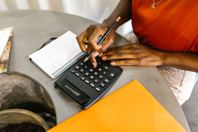 photo of a woman using a calculate, pencil and notepad